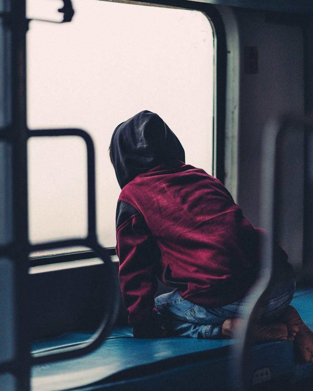 a person sitting on a bench looking out a window