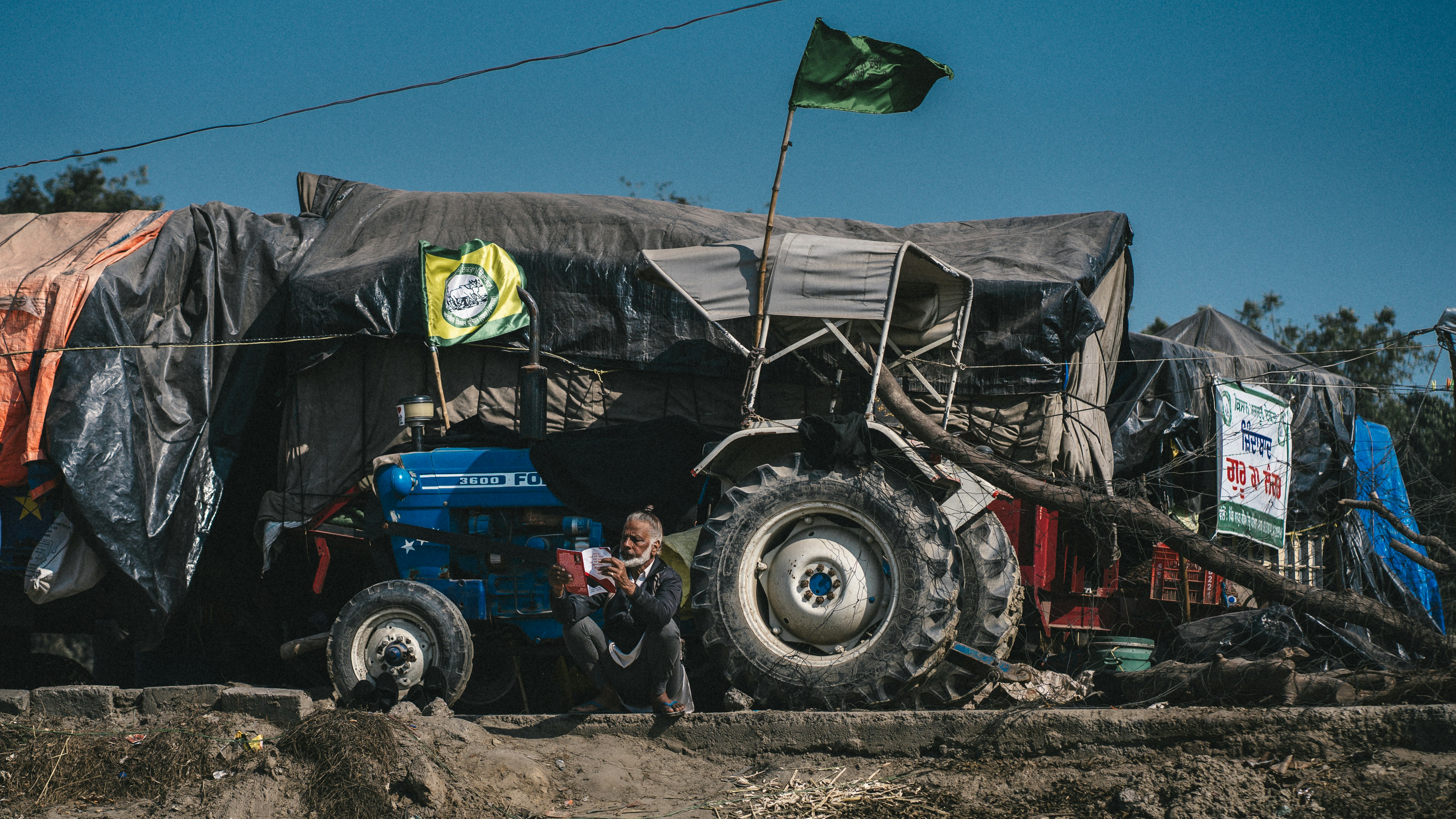 A tractor with a backhoe attachment digging a trench in a field