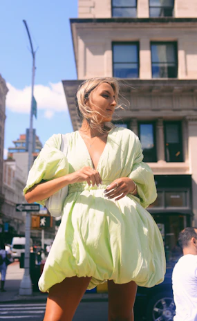 A vibrant seasonal dress flowing in the breeze on a sunlit city street.