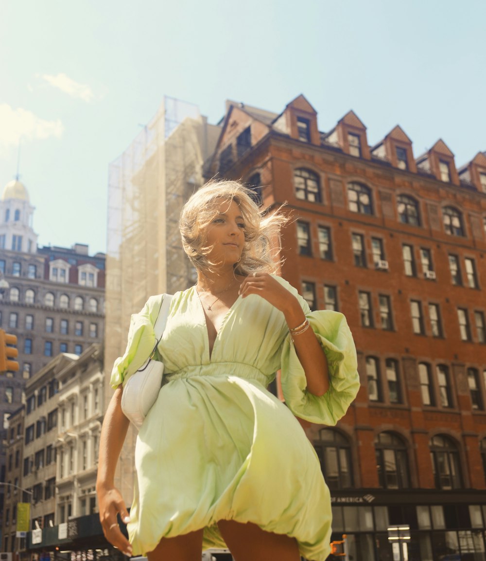 a woman in a green dress is walking down the street