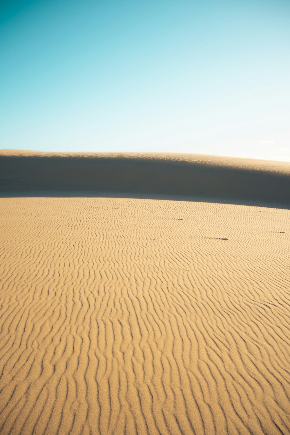 a large sand dune with a blue sky in the background