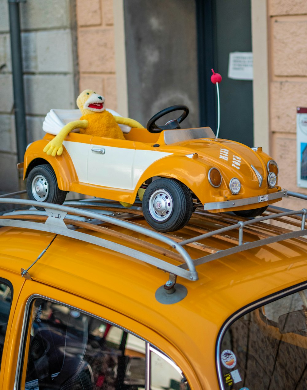 a yellow car with a stuffed animal on top of it