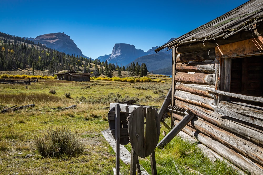 an old log cabin in the mountains with mountains in the background