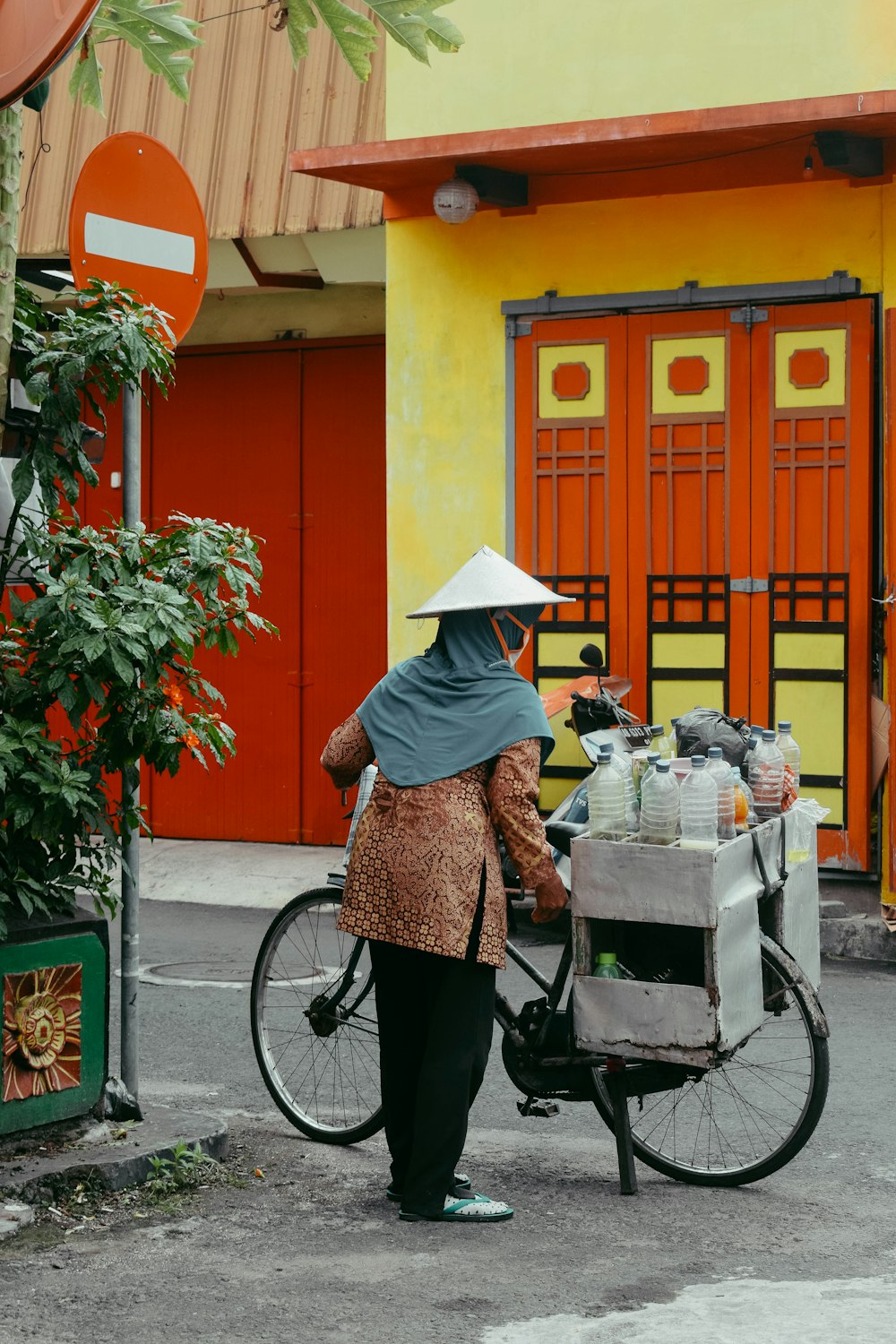 a woman on a bike with a cart full of items
