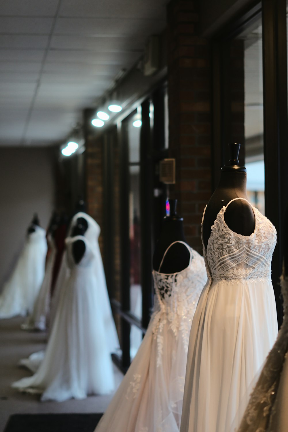 a row of wedding dresses on mannequins in front of a window