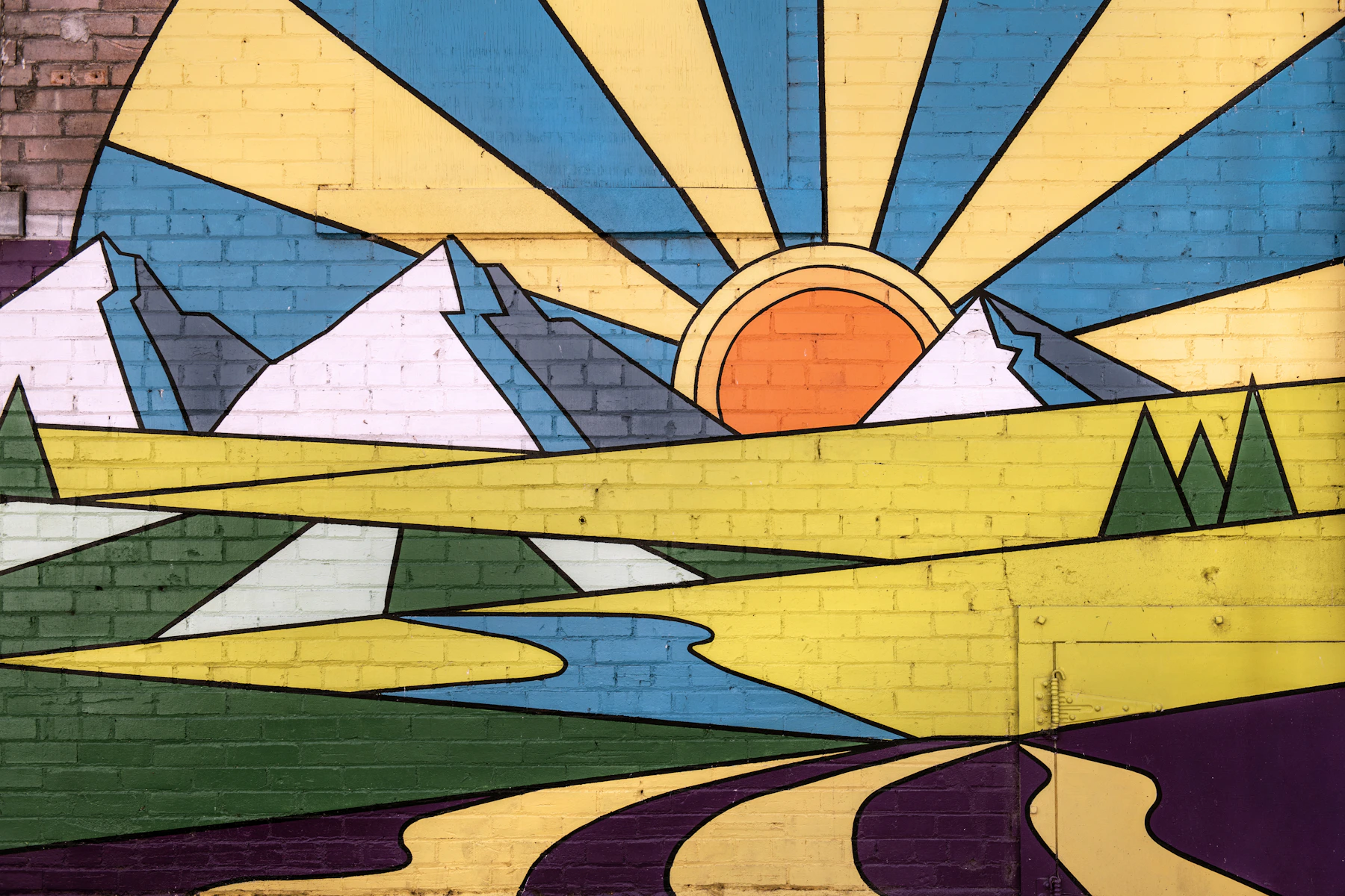 A colorful brick mural showing a sunrise, mountains, trees, and a winding river.
