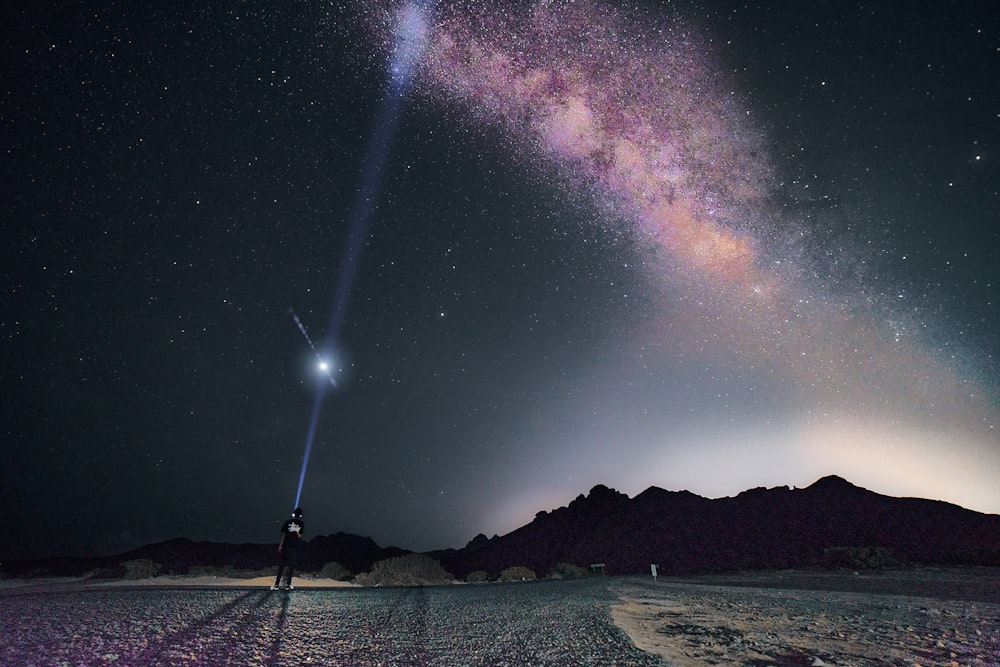 a person standing in the middle of a desert under a star filled sky