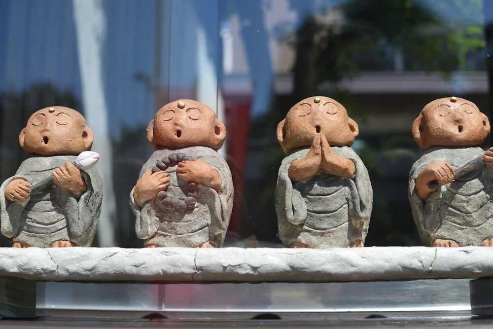 a group of little statues sitting on top of a stone bench