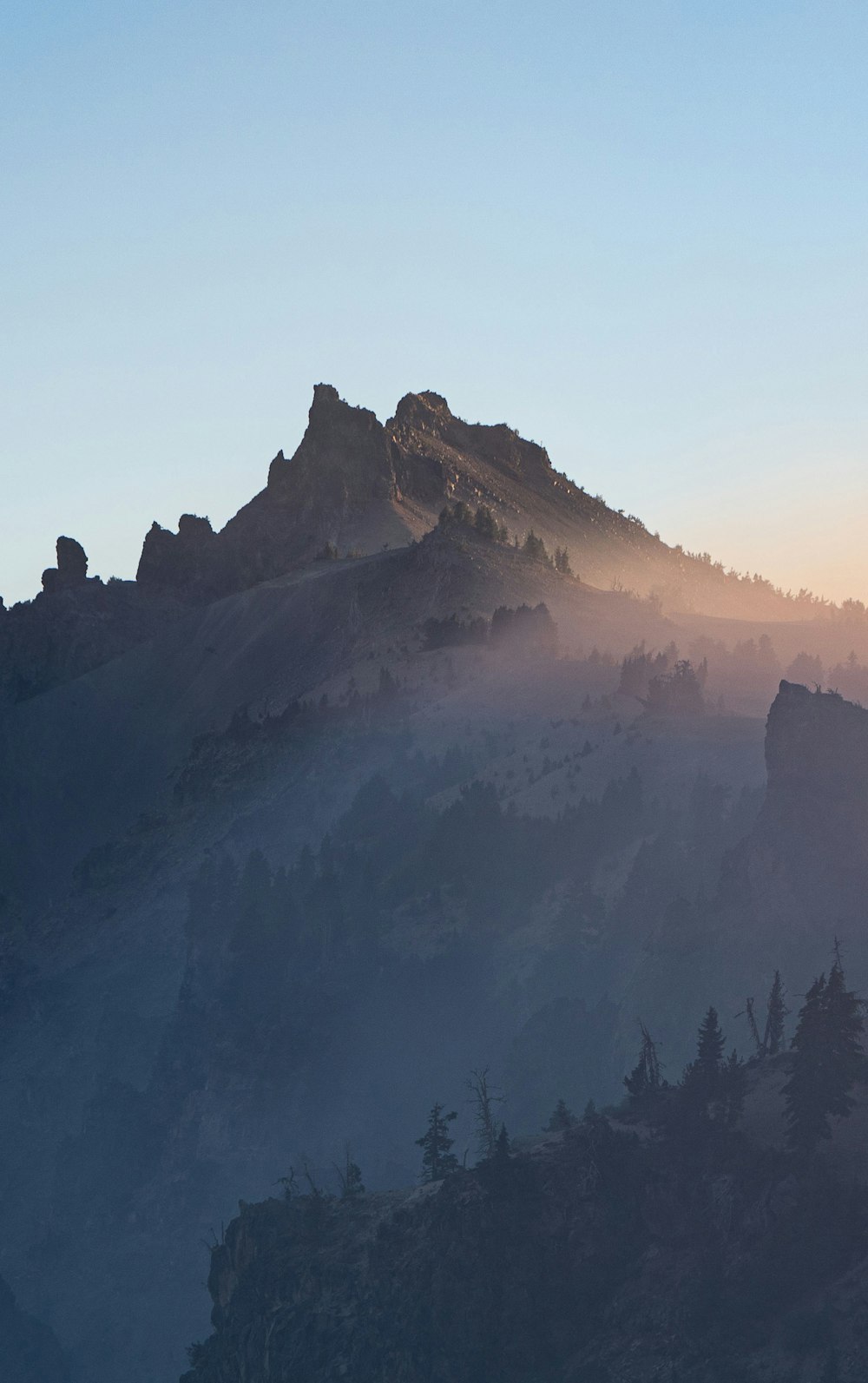 a mountain covered in fog with trees on top of it