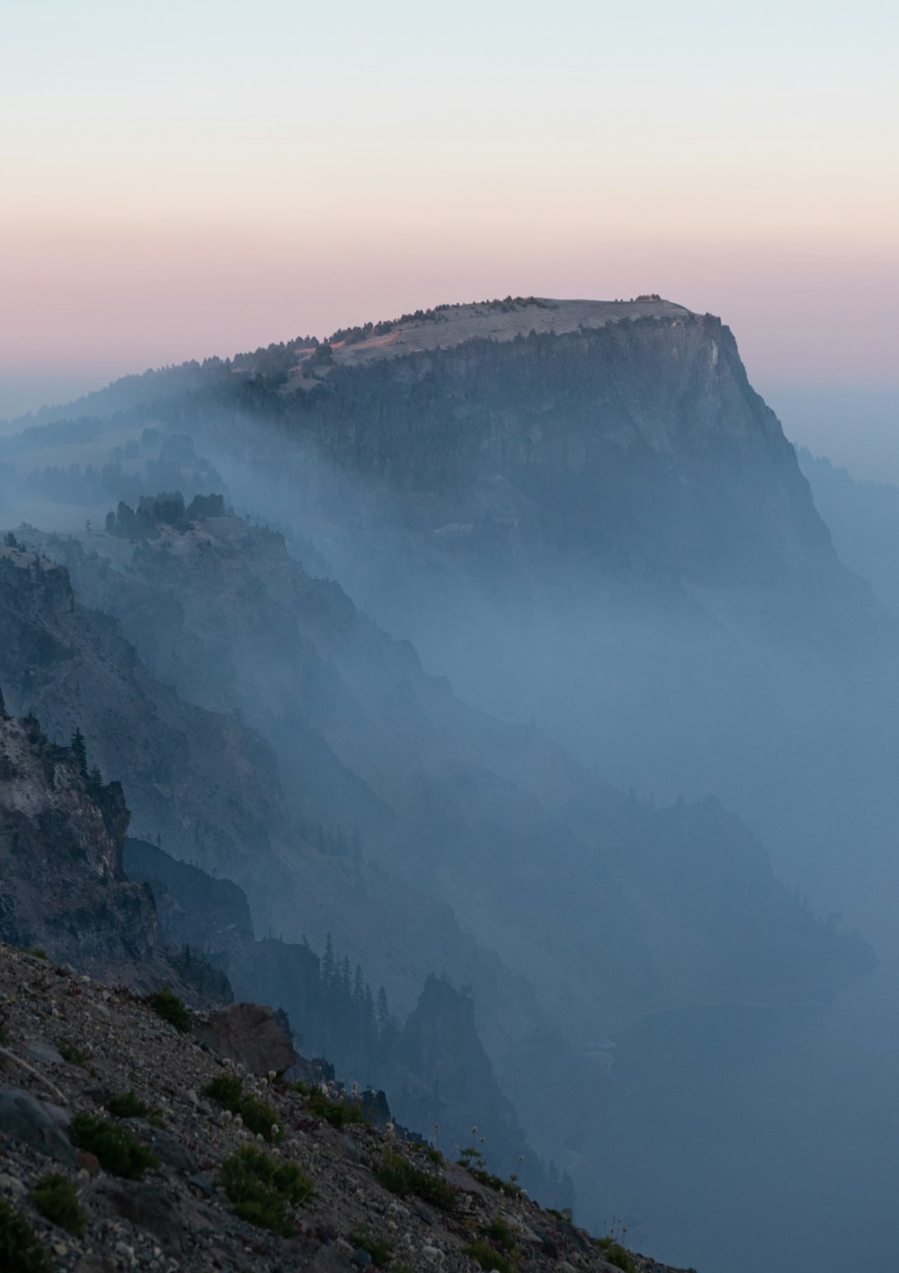 a view of a mountain with fog in the air