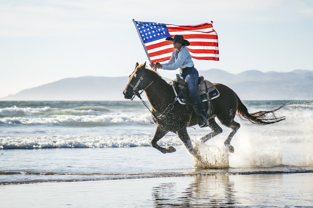 Una mujer montando a caballo con una bandera estadounidense en la espalda
