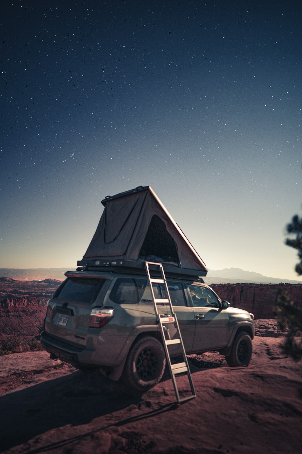 a jeep with a ladder attached to it parked in the desert