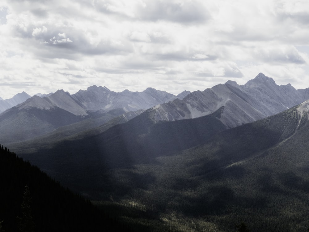 Une vue d'une chaîne de montagnes avec le soleil qui brille à travers les  nuages photo – Photo Gris Gratuite sur Unsplash