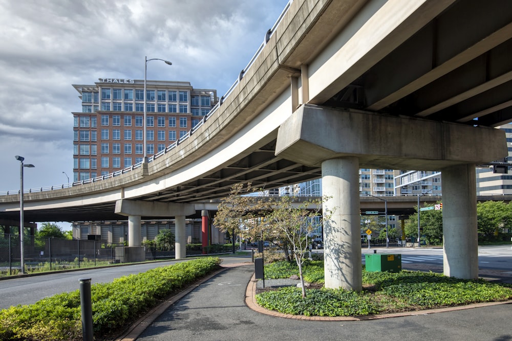 a road under a bridge with a building in the background