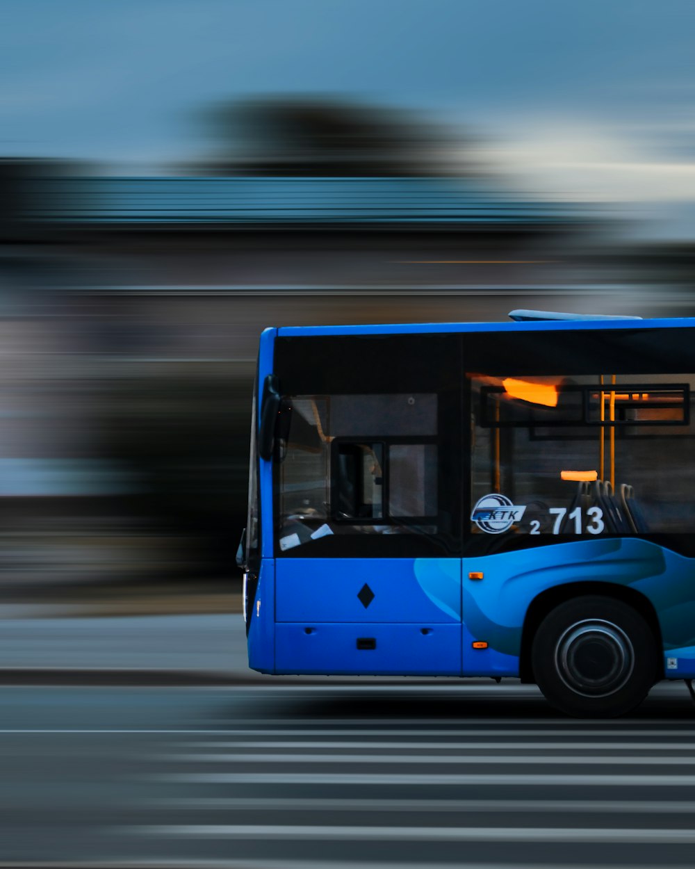Un autobús azul conduciendo por una calle al lado de un edificio alto