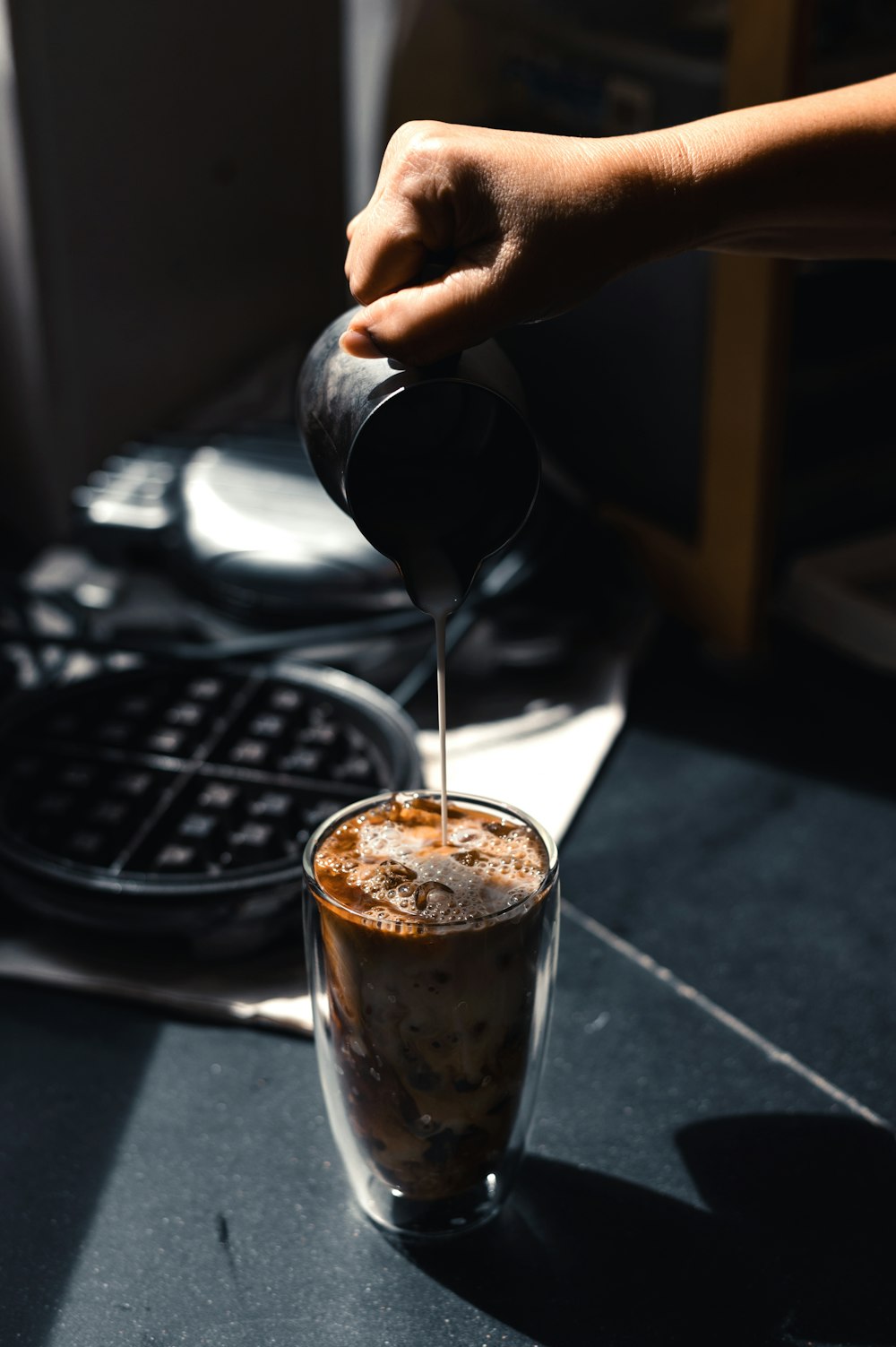 a person pours coffee into a glass