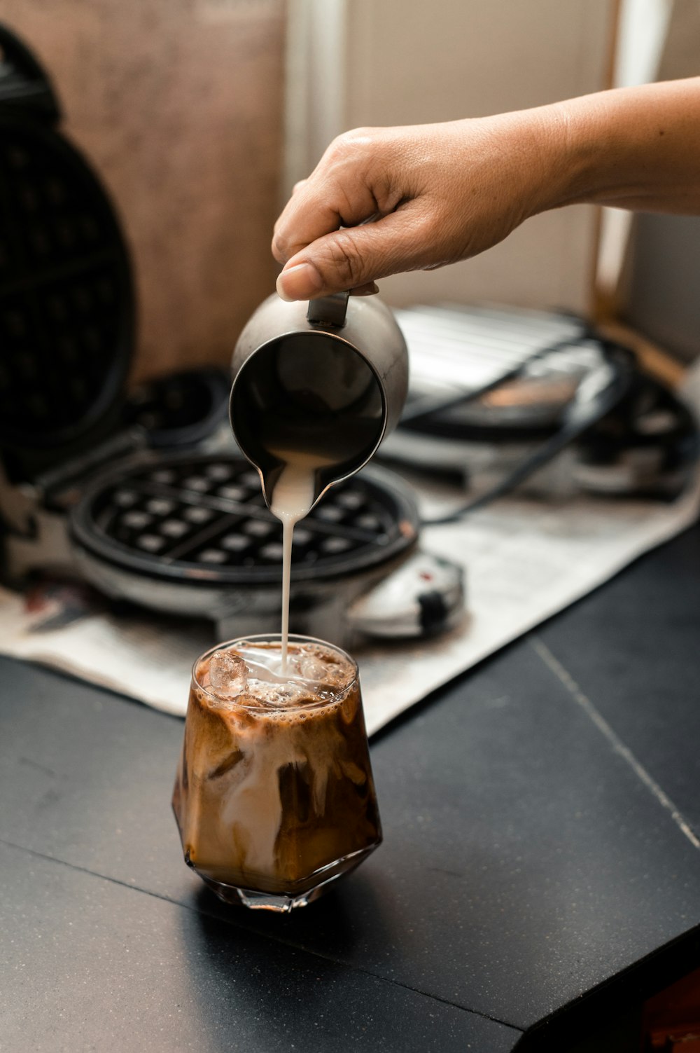 a person pours coffee into a glass