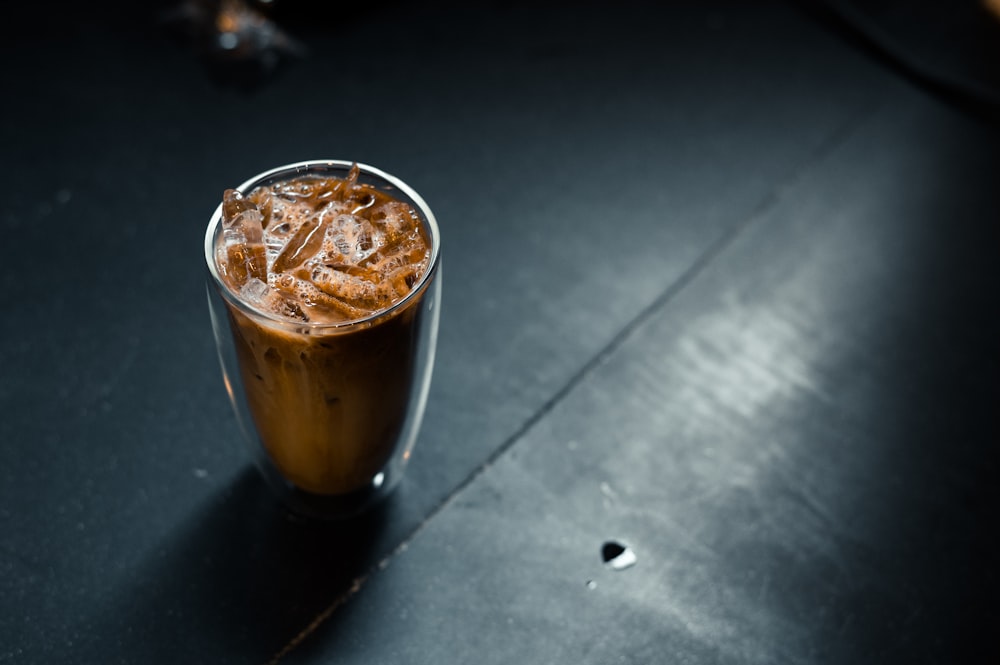 a glass of iced coffee sitting on a table