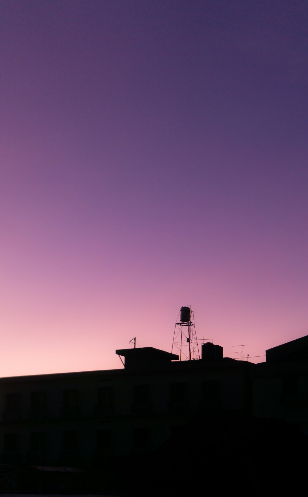a purple sky with a water tower in the distance