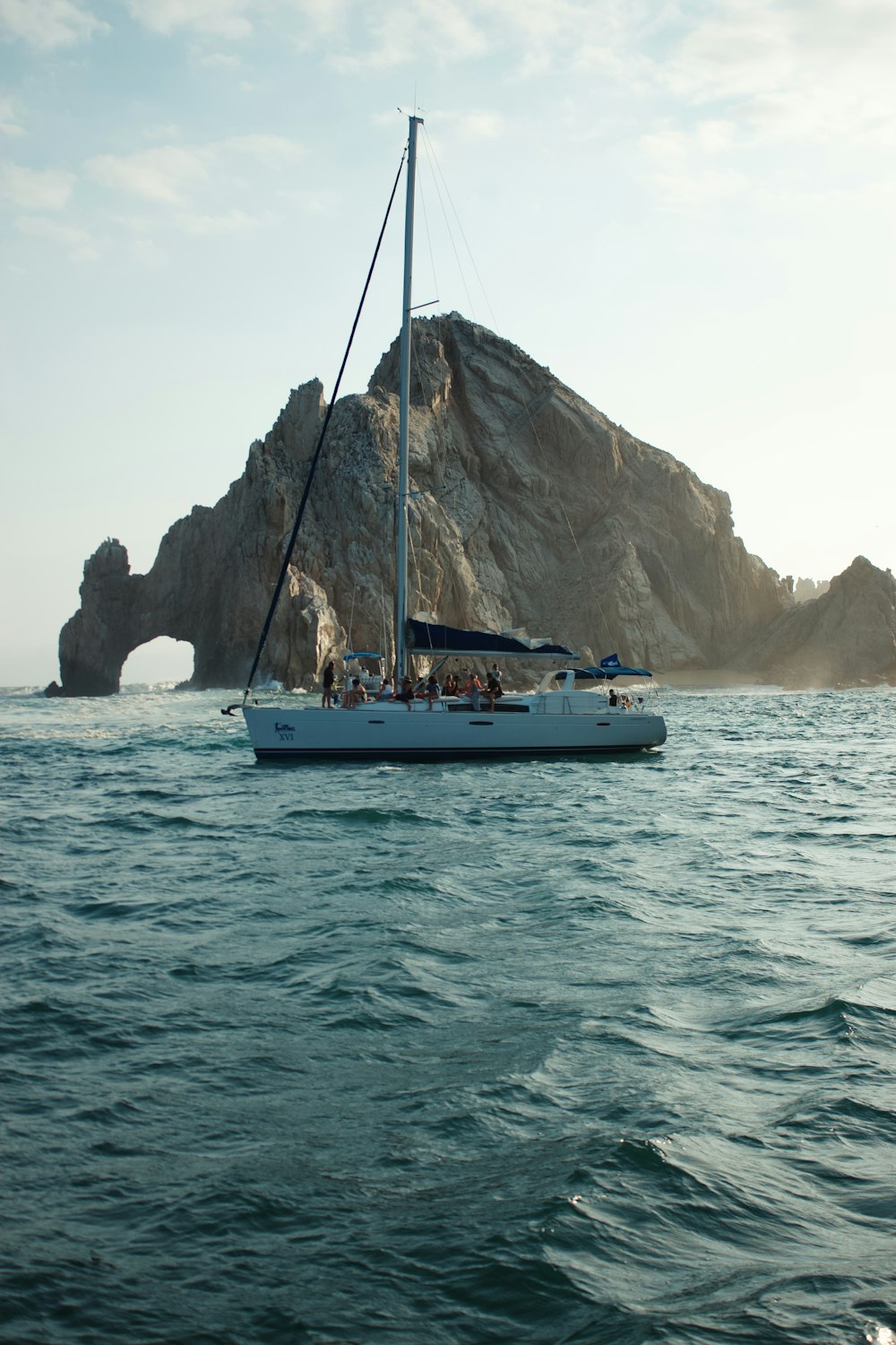 a sailboat in a body of water with a rock in the background
