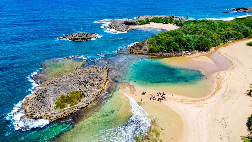 an aerial view of a sandy beach with clear blue water