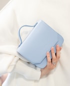 a woman holding a blue purse over her shoulder