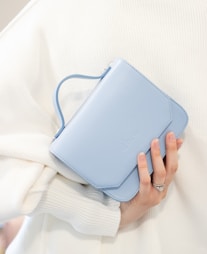 a woman holding a blue purse over her shoulder