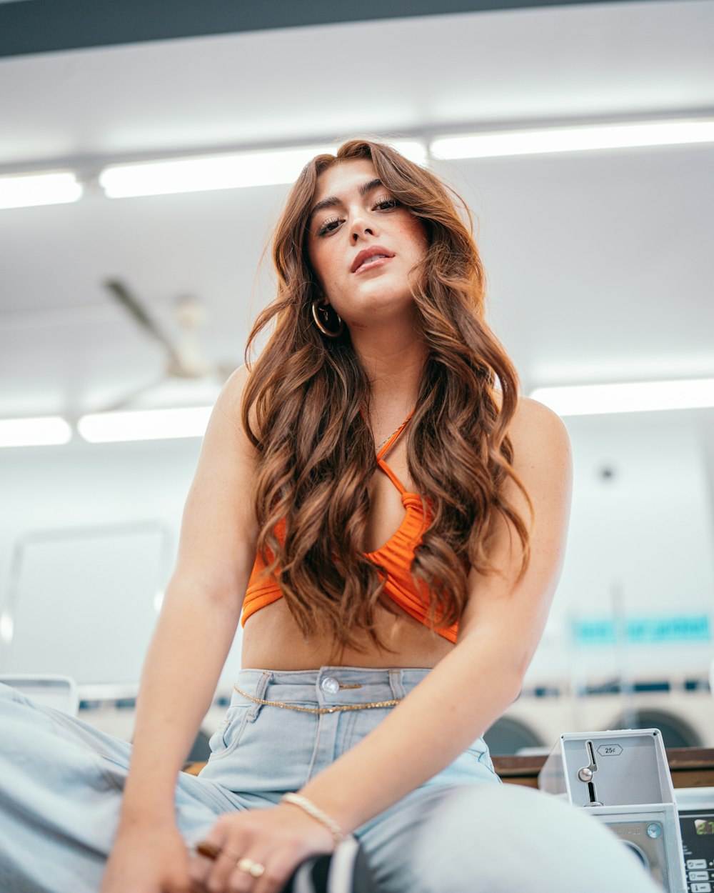 a woman in an orange top sitting on a desk