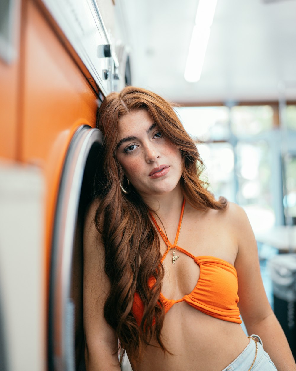 a woman in an orange bikini top leaning against a wall