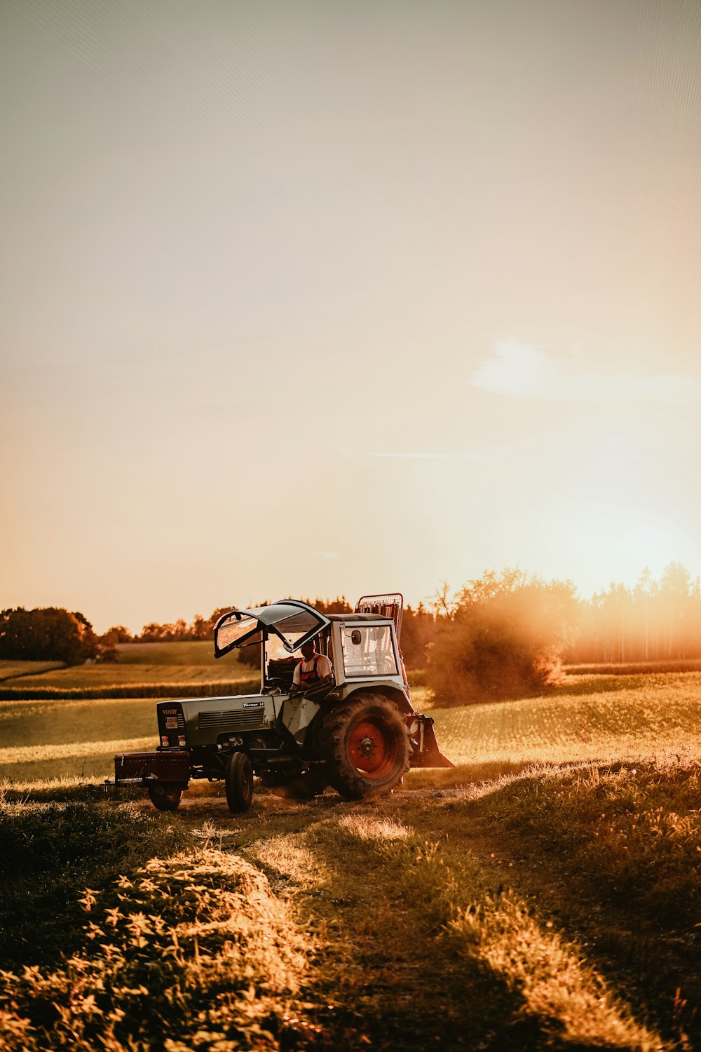 a tractor driving down a dirt road near a field