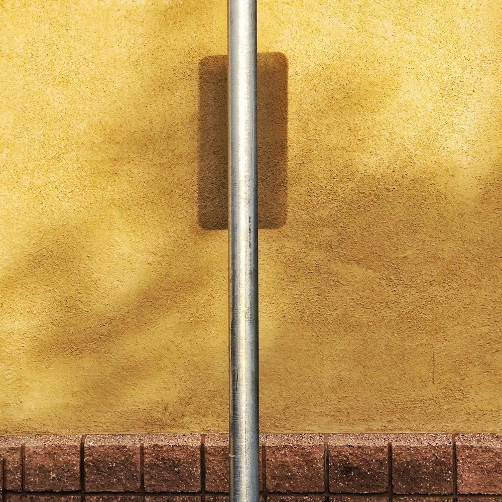 a street sign on a pole in front of a yellow wall