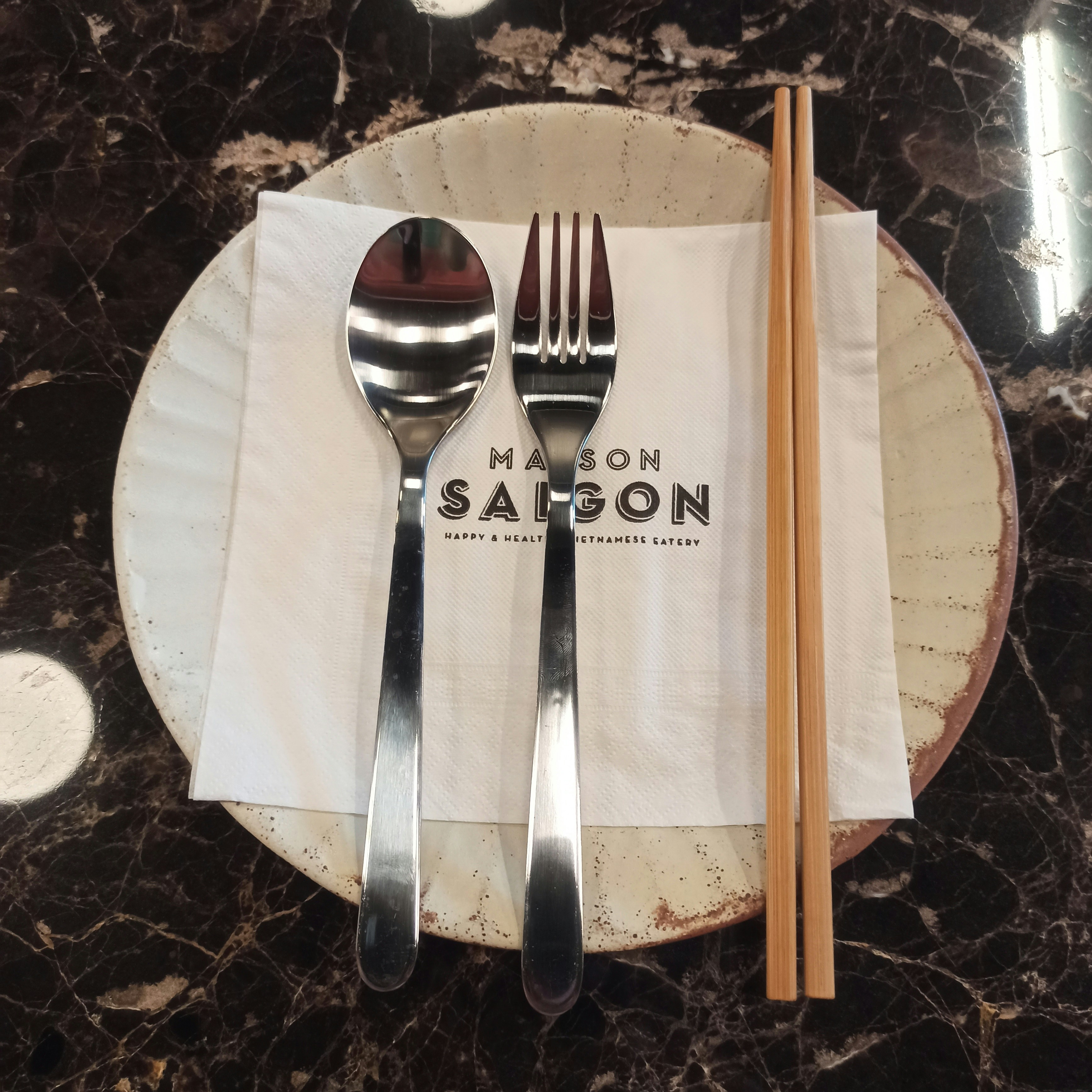 a white plate topped with silverware next to a pair of chopsticks