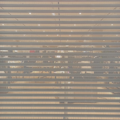 A closed metal security shutter with horizontal slats covers a storefront. Behind the shutter, interior lighting reveals an organized but slightly obscured view of a retail store with clothing racks and shelves visible.