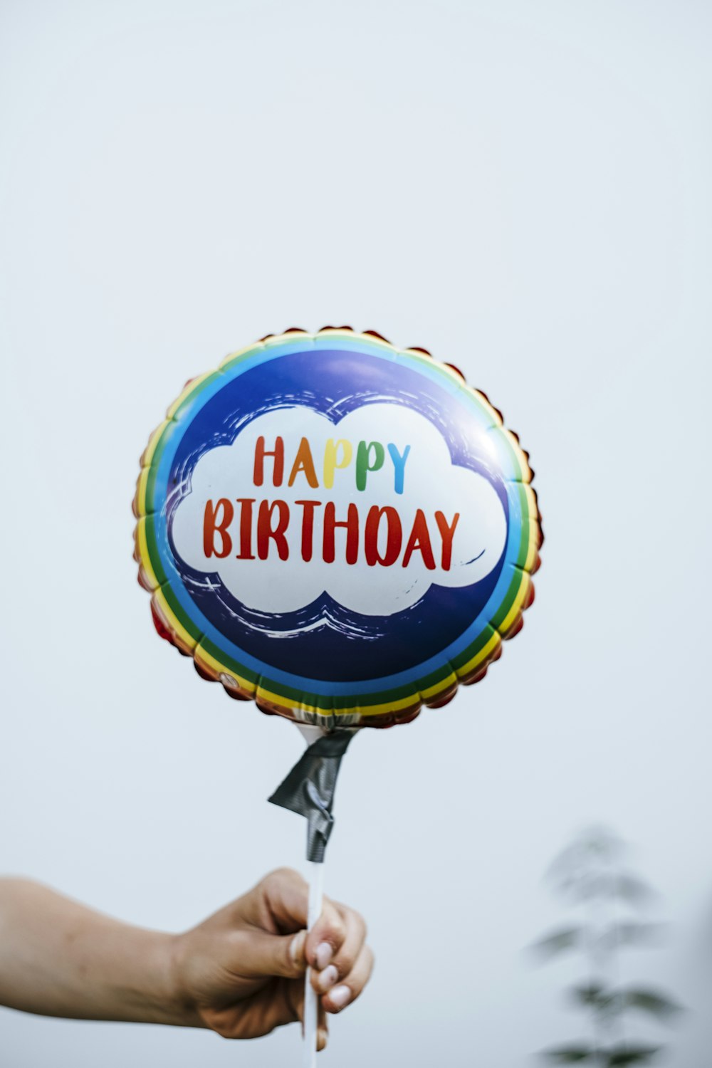 Una persona sosteniendo un globo que dice feliz cumpleaños