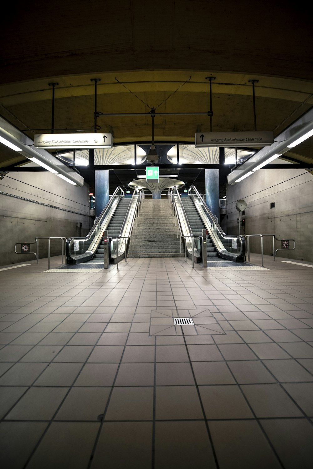 an empty subway station with escalators and tiled floors