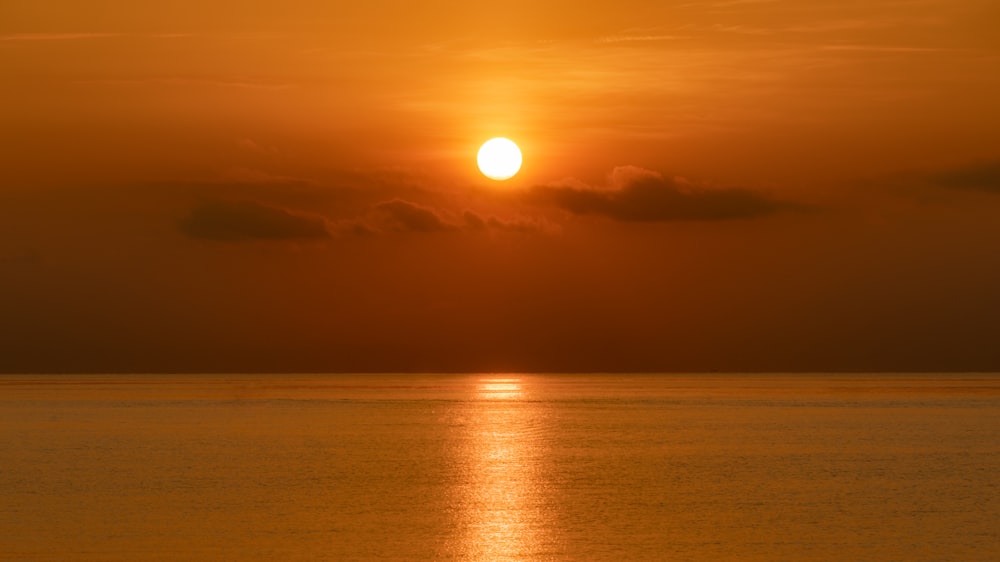 a large body of water with a sunset in the background