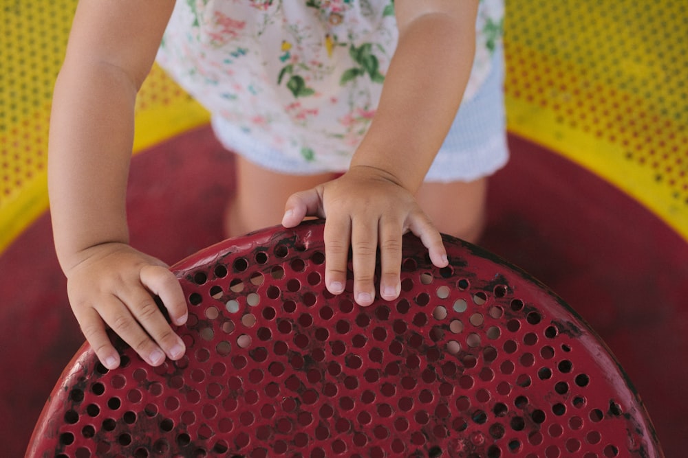 a little girl holding onto a red chair