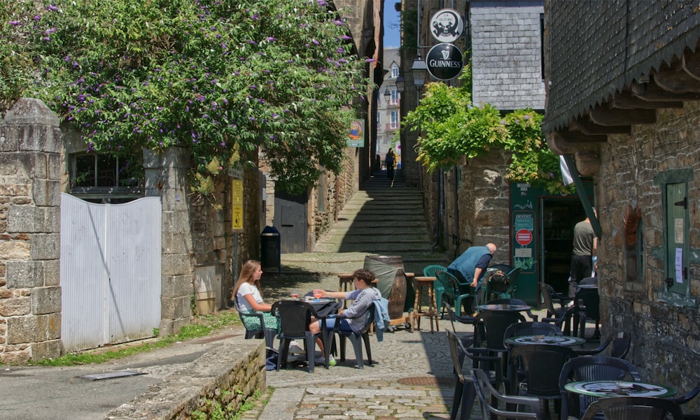 a group of people sitting at a table in an alleyway