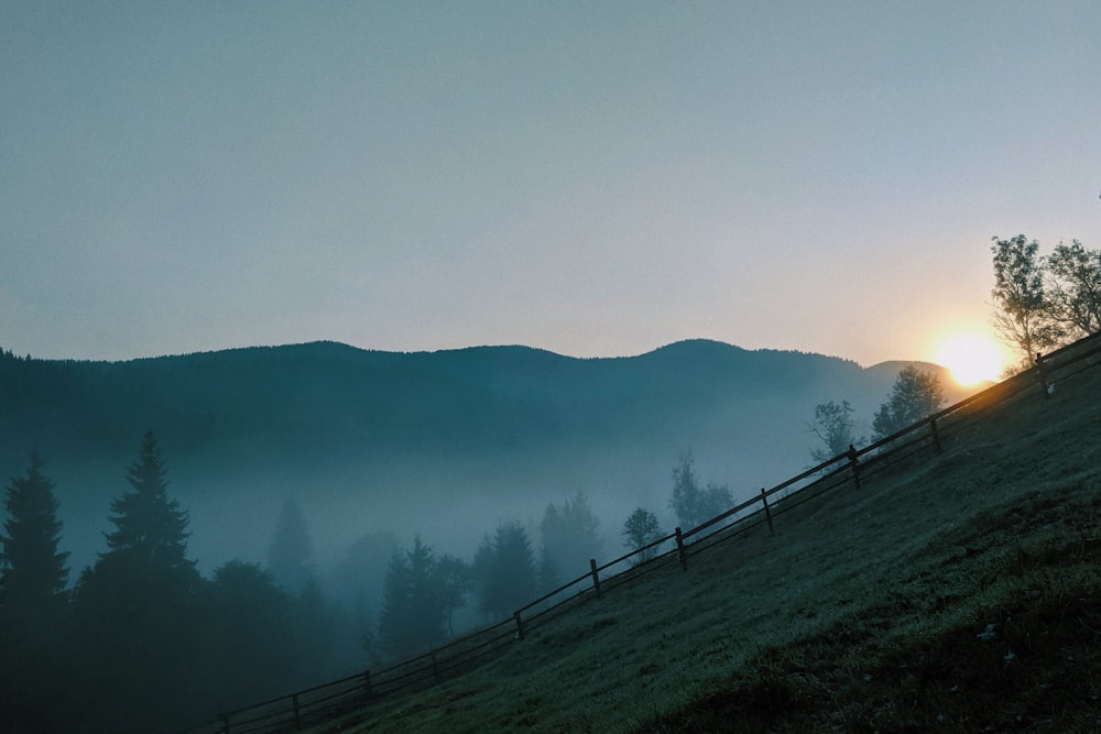 the sun is setting over the mountains in the fog