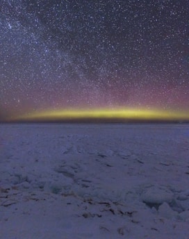 A vast icy Greenland landscape under a soft pink Arctic sky.
