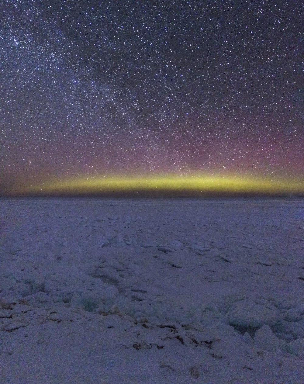 a view of the night sky with stars and the aurora in the distance