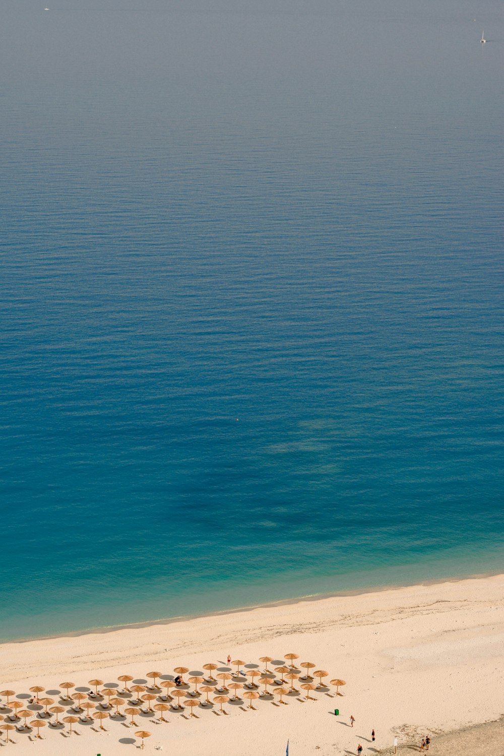 an aerial view of a beach with umbrellas and chairs