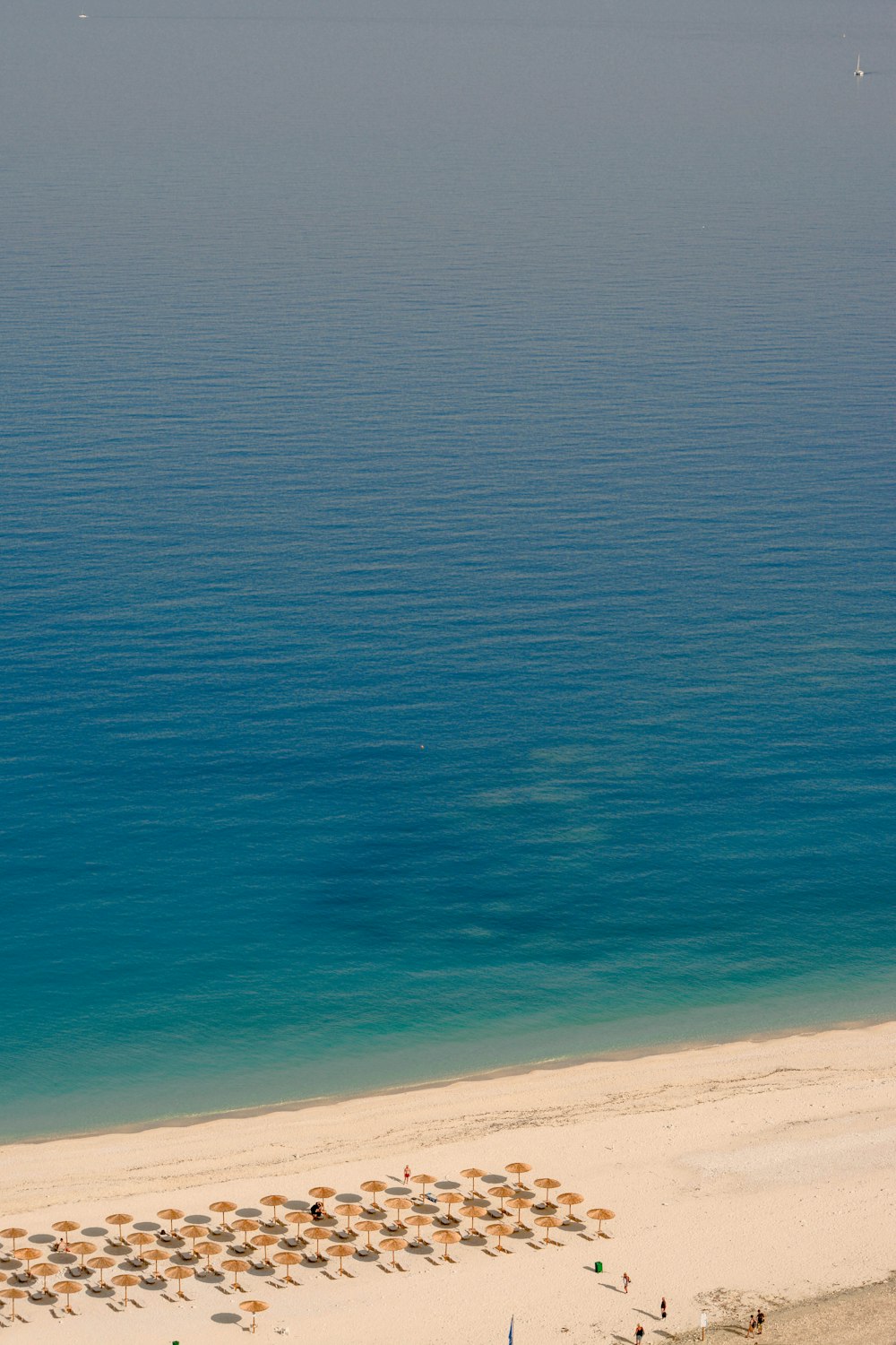 Luftaufnahme eines Strandes mit Sonnenschirmen und Stühlen