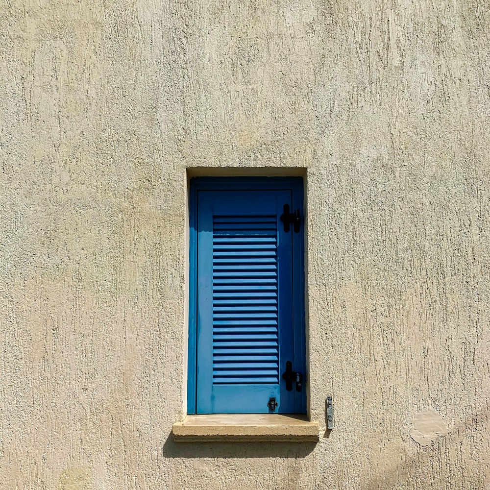 a blue window on a stucco wall with blue shutters