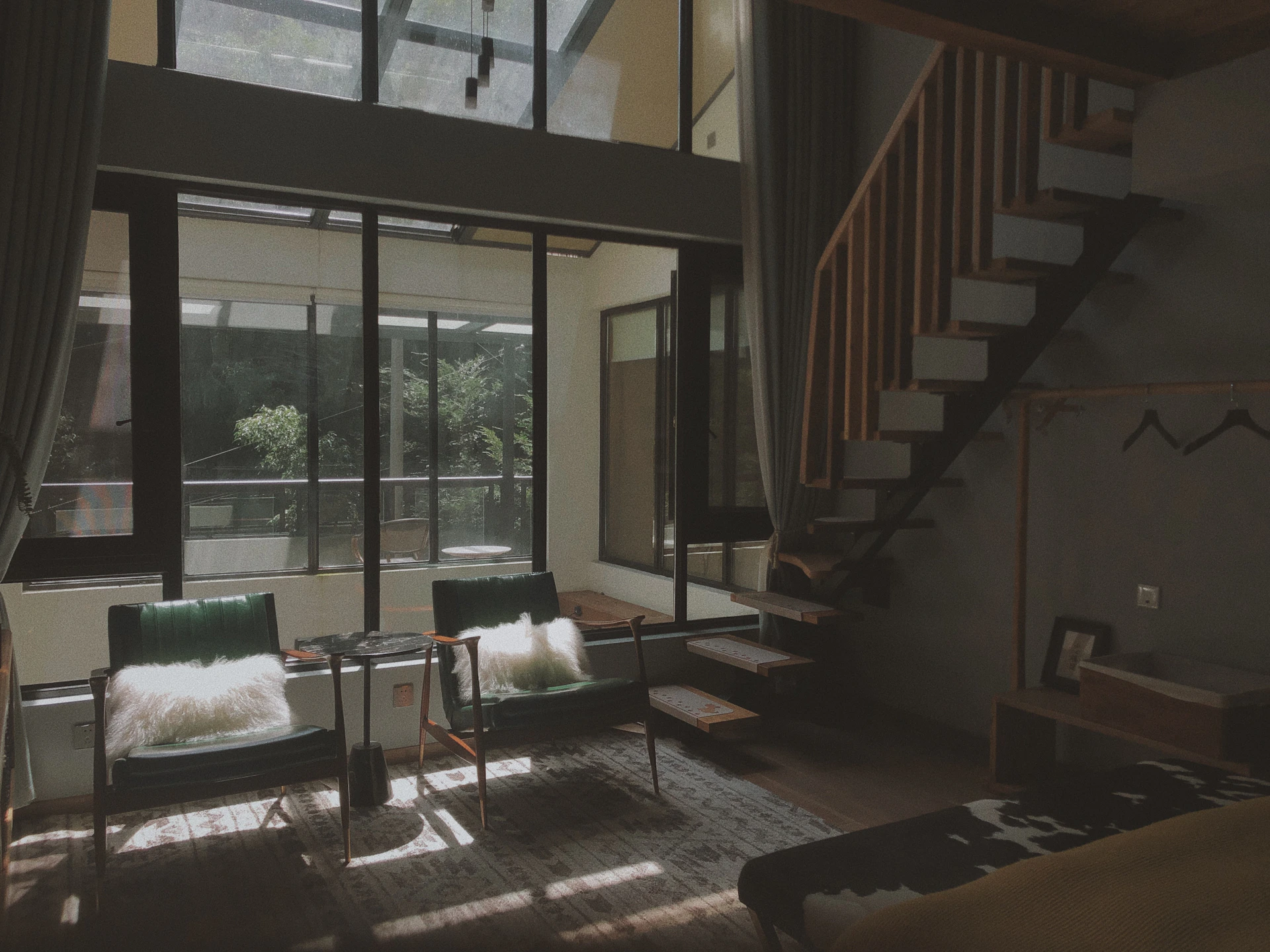 A bright, airy living room in a Troff homestay unit, featuring minimalist decor with soft natural light streaming through large windows.
