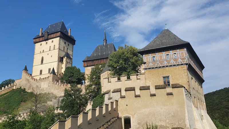 Karlštejn Castle's Great Tower above the tree line with the village of Karlštejn in the valley below