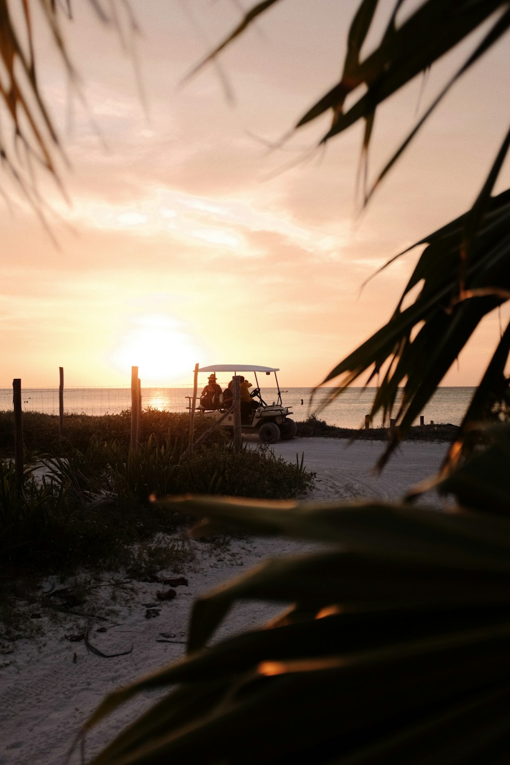 a golf cart is parked on the beach at sunset
