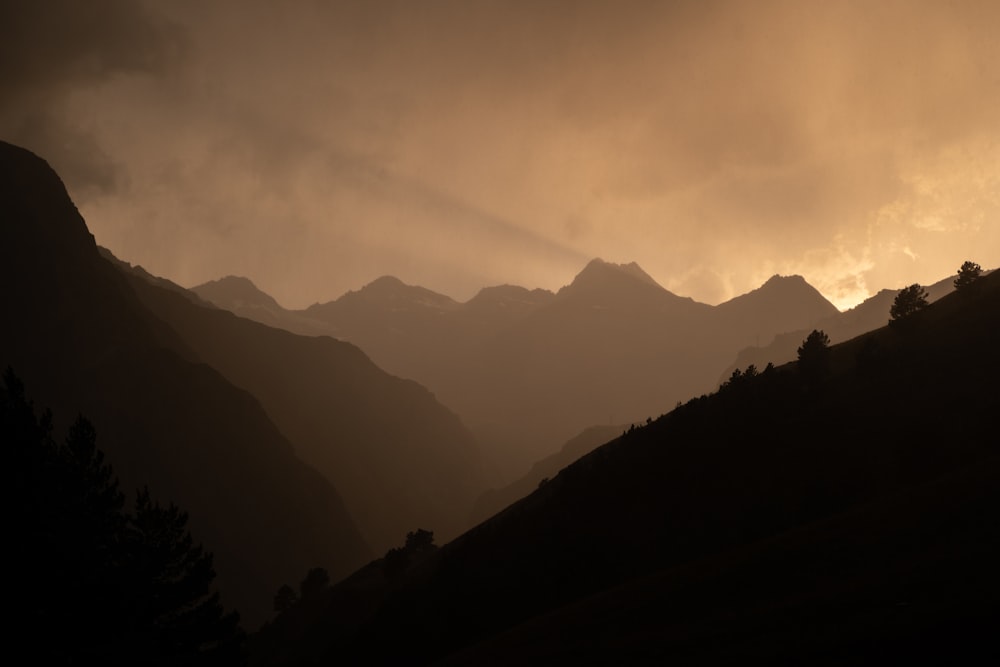 the sun is shining through the clouds over the mountains