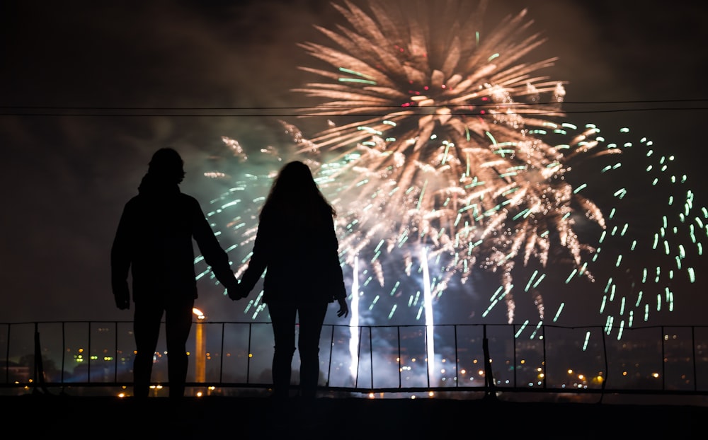 a couple holding hands as fireworks go off in the background