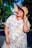 A stylish woman wearing a colorful dress in a bright outdoor setting.